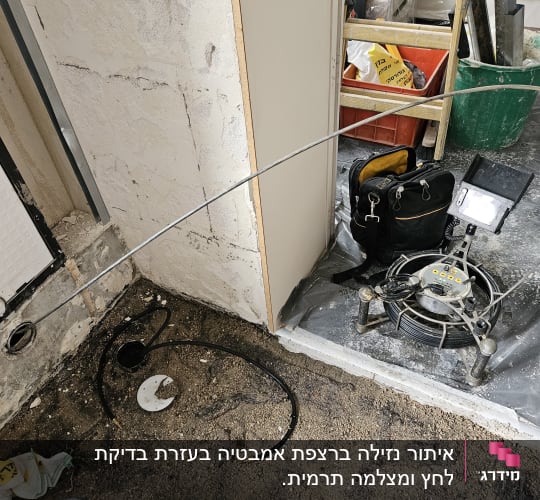 ציוד לאיתור נזילות, כולל מצלמה וכבלים על רצפה חשופה